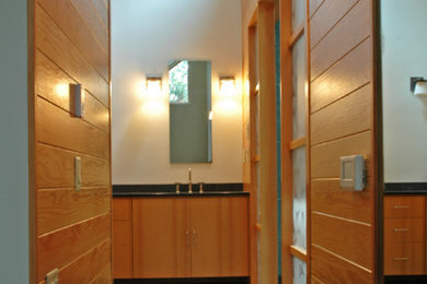 Modelo de cuarto de baño principal actual de tamaño medio con lavabo bajoencimera, armarios con paneles lisos, puertas de armario de madera oscura, encimera de cuarcita, baldosas y/o azulejos verdes, baldosas y/o azulejos de piedra, paredes blancas y suelo de pizarra