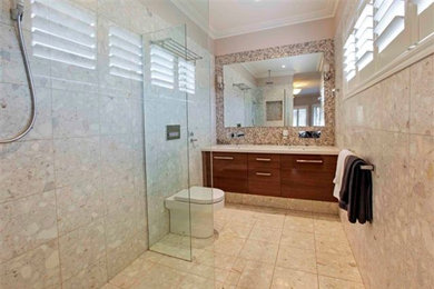 Cette image montre une salle de bain design avec un lavabo encastré, un placard à porte plane, un plan de toilette en quartz modifié, une douche ouverte, WC suspendus, un carrelage multicolore, mosaïque et un mur beige.