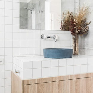 Photo of a contemporary bathroom in Gold Coast - Tweed with light wood cabinets, white tile, ceramic tile, tile benchtops, white benchtops, a single vanity, a floating vanity, flat-panel cabinets, a vessel sink and grey floor.