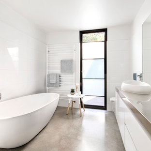Photo of a large contemporary master bathroom in Melbourne with grey cabinets, a freestanding tub, a corner shower, a one-piece toilet, white tile, ceramic tile, yellow walls, concrete floors, a vessel sink, engineered quartz benchtops, a hinged shower door, grey benchtops, a single vanity and a floating vanity.
