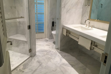 Mid-sized trendy master white tile and marble tile marble floor and white floor alcove shower photo in Los Angeles with furniture-like cabinets, white cabinets, a one-piece toilet, white walls, an undermount sink, solid surface countertops and a hinged shower door