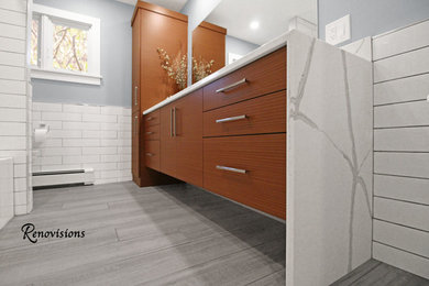 Example of a mid-sized trendy kids' white tile and ceramic tile porcelain tile and gray floor bathroom design in Boston with flat-panel cabinets, medium tone wood cabinets, a two-piece toilet, blue walls, an undermount sink, quartz countertops and white countertops