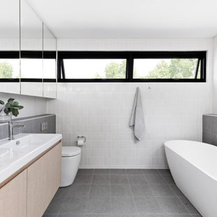 Design ideas for a mid-sized contemporary master bathroom in Sydney with light wood cabinets, a freestanding tub, white tile, gray tile, ceramic tile, white walls, porcelain floors, grey floor, a double vanity, a floating vanity, flat-panel cabinets, a console sink and white benchtops.