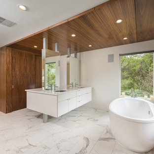 Modelo de cuarto de baño principal y vestidor, moderno, grande, con armarios con paneles lisos, puertas de armario blancas, bañera exenta, ducha abierta, sanitario de una pieza, baldosas y/o azulejos blancos, baldosas y/o azulejos de porcelana, paredes blancas, suelo de baldosas de porcelana, lavabo bajoencimera, encimera de cuarzo compacto, suelo blanco y ducha abierta