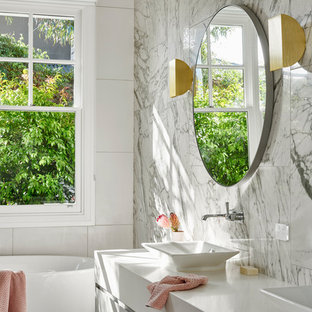 This is an example of a contemporary bathroom in Geelong with flat-panel cabinets, grey cabinets, a freestanding tub, white tile, a vessel sink, grey floor and white benchtops.