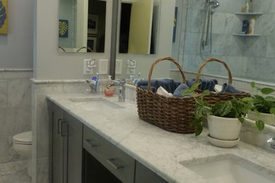 Example of a mid-sized 1950s master white tile and stone tile mosaic tile floor and white floor bathroom design in Cincinnati with recessed-panel cabinets, gray cabinets, a one-piece toilet, gray walls, an undermount sink and marble countertops