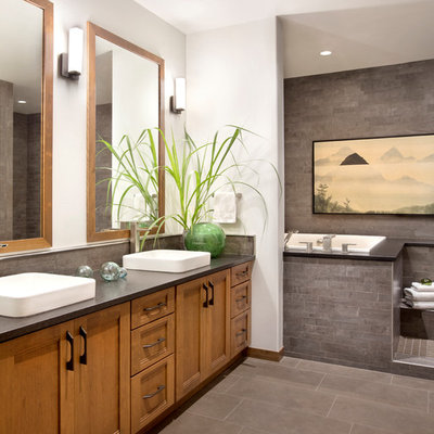 Inspiration for a rustic master gray tile gray floor drop-in bathtub remodel in Other with a vessel sink, recessed-panel cabinets and medium tone wood cabinets