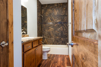 Mid-sized elegant dark wood floor alcove bathtub photo in Other with a drop-in sink, flat-panel cabinets, dark wood cabinets, granite countertops and white walls