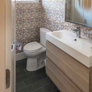 Example of a small trendy 3/4 slate floor and black floor bathroom design in Detroit with flat-panel cabinets, light wood cabinets, a one-piece toilet, beige walls, a trough sink and quartzite countertops