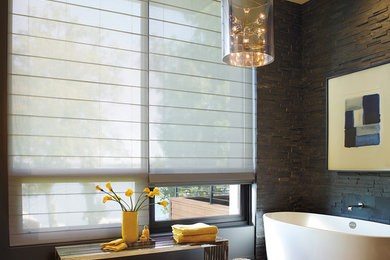 Diseño de cuarto de baño principal contemporáneo de tamaño medio con bañera exenta, paredes negras y suelo de madera clara