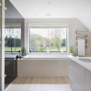 Design ideas for a large contemporary bathroom in London with flat-panel cabinets, white cabinets, a built-in bath, beige walls, a submerged sink, beige floors and beige worktops.