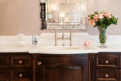 На фото: большая главная ванная комната в классическом стиле с темными деревянными фасадами, фасадами с декоративным кантом, отдельно стоящей ванной, открытым душем, унитазом-моноблоком, белой плиткой, каменной плиткой, розовыми стенами, полом из травертина, врезной раковиной, мраморной столешницей и бежевым полом