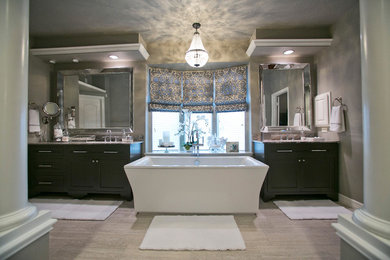 ヒューストンにある高級なトランジショナルスタイルのおしゃれな浴室 (アンダーカウンター洗面器、家具調キャビネット、黒いキャビネット、大理石の洗面台、置き型浴槽、バリアフリー、一体型トイレ	、グレーのタイル、セラミックタイル) の写真