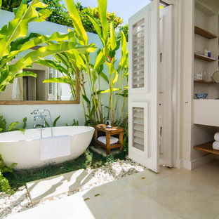 Esempio di una stanza da bagno padronale tropicale con vasca freestanding e pavimento beige