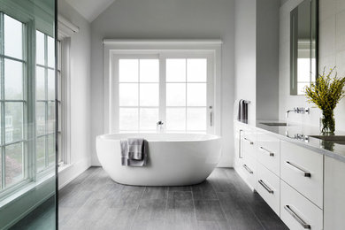 Inspiration for a mid-sized coastal master white tile gray floor and porcelain tile bathroom remodel in New York with flat-panel cabinets, white cabinets, white walls, an undermount sink, a hinged shower door and gray countertops
