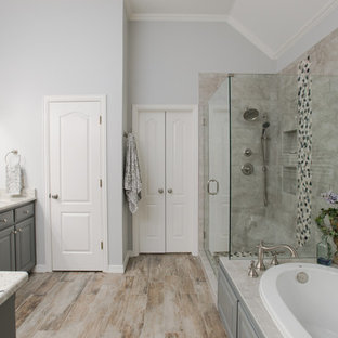 Mid-sized country master gray tile and porcelain tile porcelain tile and gray floor bathroom photo in Dallas with raised-panel cabinets, gray cabinets, a two-piece toilet, gray walls, an undermount sink, granite countertops, a hinged shower door and white countertops