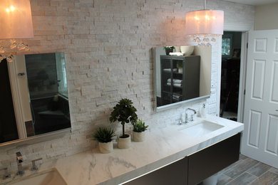 Mid-sized minimalist brown tile and porcelain tile porcelain tile bathroom photo in Chicago with glass-front cabinets, gray cabinets, a one-piece toilet, gray walls, an undermount sink and marble countertops