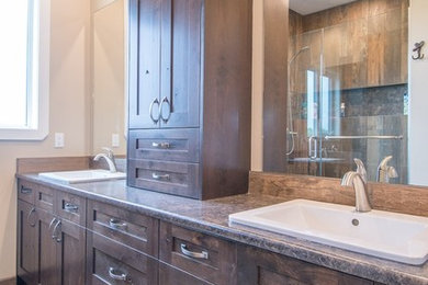 Example of a mid-sized mountain style 3/4 brown tile and porcelain tile porcelain tile and brown floor alcove shower design in Calgary with shaker cabinets, dark wood cabinets, beige walls, a drop-in sink, quartz countertops, a hinged shower door and gray countertops