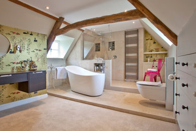 Large contemporary ensuite bathroom in Oxfordshire with dark wood cabinets, beige tiles, flat-panel cabinets, a freestanding bath, a walk-in shower, a wall mounted toilet, porcelain tiles, multi-coloured walls, porcelain flooring, beige floors, an open shower, a feature wall, a floating vanity unit and exposed beams.