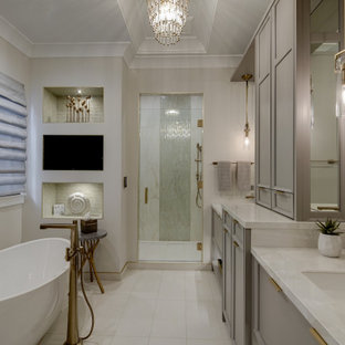 Inspiration för ett vintage vit vitt en-suite badrum, med luckor med infälld panel, grå skåp, ett fristående badkar, en dusch i en alkov, beige väggar, ett integrerad handfat, beiget golv och dusch med gångjärnsdörr