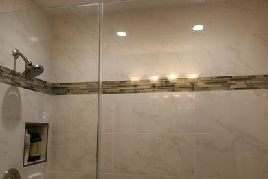 Elegant brown tile and matchstick tile alcove shower photo in Tampa with white walls and a hinged shower door