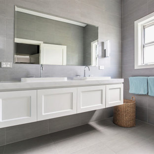 Idee per una stanza da bagno con doccia tradizionale di medie dimensioni con ante in stile shaker, ante bianche, doccia alcova, WC monopezzo, piastrelle grigie, piastrelle di pietra calcarea, pareti grigie, pavimento in gres porcellanato, lavabo da incasso, top in marmo, pavimento grigio, porta doccia a battente e top grigio