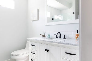 Пример оригинального дизайна: ванная комната среднего размера в стиле неоклассика (современная классика) с фасадами в стиле шейкер, белыми фасадами, унитазом-моноблоком, белой плиткой, плиткой кабанчик, серыми стенами, полом из керамической плитки, врезной раковиной, мраморной столешницей, душем с раздвижными дверями и белой столешницей