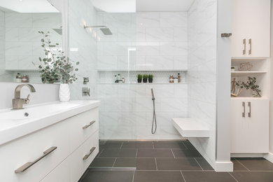 Modern inredning av ett mellanstort vit vitt en-suite badrum, med släta luckor, vita skåp, en öppen dusch, en toalettstol med hel cisternkåpa, vit kakel, porslinskakel, grå väggar, klinkergolv i porslin, ett integrerad handfat, svart golv och med dusch som är öppen