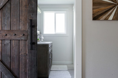 Example of a mid-sized transitional master white tile and ceramic tile ceramic tile, brown floor, double-sink and shiplap wall bathroom design in Other with shaker cabinets, gray cabinets, a two-piece toilet, gray walls, an undermount sink, quartz countertops, white countertops and a freestanding vanity