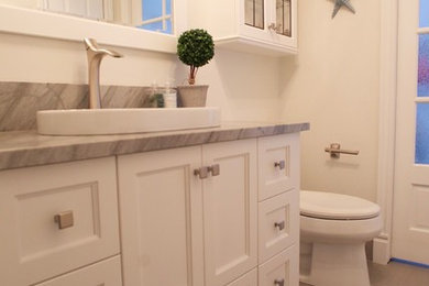 Mittelgroßes Modernes Duschbad mit Schrankfronten mit vertiefter Füllung, weißen Schränken, Wandtoilette mit Spülkasten, beiger Wandfarbe, Porzellan-Bodenfliesen, Aufsatzwaschbecken, Quarzit-Waschtisch und grauem Boden in Montreal