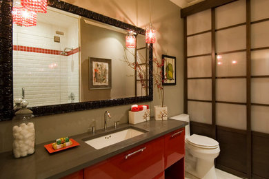 Example of a mid-sized 3/4 porcelain tile and white floor alcove shower design in Richmond with flat-panel cabinets, red cabinets, a one-piece toilet, green walls, an undermount sink, solid surface countertops and a hinged shower door