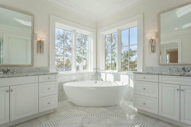 Example of a large tuscan master white tile and stone tile marble floor and white floor freestanding bathtub design in Tampa with an undermount sink, raised-panel cabinets, white cabinets, marble countertops and white walls