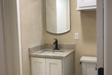 Réalisation d'une douche en alcôve design avec un placard à porte shaker, des portes de placard blanches, WC séparés, un mur jaune, un sol en carrelage de porcelaine, un lavabo encastré, un plan de toilette en granite, un sol beige et un plan de toilette gris.