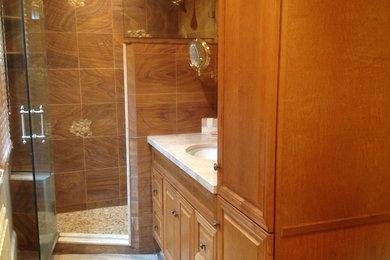 Inspiration for a small transitional master multicolored tile and stone tile mosaic tile floor alcove shower remodel in New York with an undermount sink, raised-panel cabinets, medium tone wood cabinets and marble countertops