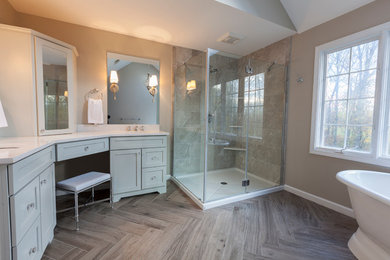 This is an example of a medium sized traditional ensuite bathroom in New York with flat-panel cabinets, grey cabinets, a freestanding bath, a corner shower, a two-piece toilet, grey tiles, porcelain tiles, grey walls, porcelain flooring, a submerged sink, engineered stone worktops, grey floors and a hinged door.