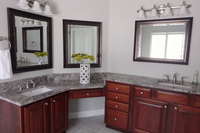 Mid-sized transitional master gray tile and porcelain tile porcelain tile bathroom photo in Austin with raised-panel cabinets, medium tone wood cabinets, gray walls, an undermount sink and granite countertops