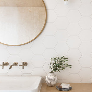 Idéer för ett mellanstort nordiskt beige en-suite badrum, med släta luckor, skåp i ljust trä, ett undermonterat badkar, en dusch/badkar-kombination, en toalettstol med hel cisternkåpa, vit kakel, keramikplattor, vita väggar, ett fristående handfat, träbänkskiva, beiget golv och med dusch som är öppen