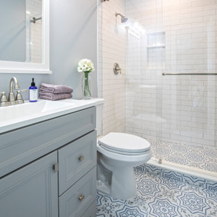 Esempio di una piccola stanza da bagno con doccia country con consolle stile comò, ante grigie, doccia alcova, WC a due pezzi, piastrelle bianche, piastrelle in ceramica, pareti blu, pavimento in gres porcellanato, lavabo integrato, top in superficie solida, pavimento multicolore, porta doccia scorrevole, top bianco, nicchia, un lavabo e mobile bagno freestanding