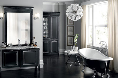 Diseño de cuarto de baño clásico con puertas de armario negras, encimera de granito, bañera exenta, paredes grises y suelo de madera oscura