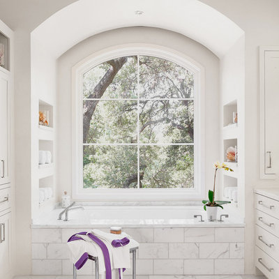 Trendy alcove bathtub photo in Austin with white cabinets and a niche