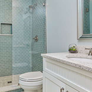 Ispirazione per una stanza da bagno con doccia costiera di medie dimensioni con ante in stile shaker, ante bianche, doccia aperta, WC monopezzo, piastrelle blu, piastrelle di vetro, pareti blu, pavimento in gres porcellanato, lavabo sottopiano, top in vetro riciclato, pavimento bianco e doccia aperta