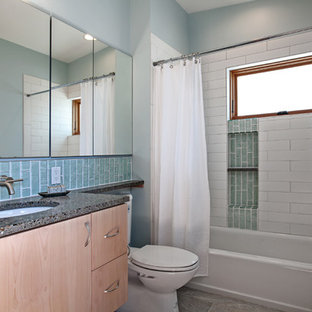 Foto di una stanza da bagno per bambini minimal di medie dimensioni con lavabo sottopiano, ante lisce, ante in legno chiaro, top in vetro riciclato, vasca ad alcova, vasca/doccia, WC monopezzo, piastrelle blu, piastrelle di vetro, pareti bianche e pavimento in gres porcellanato