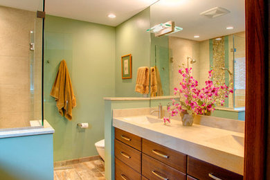 Inredning av ett modernt litet en-suite badrum, med ett integrerad handfat, släta luckor, skåp i mörkt trä, bänkskiva i akrylsten, en kantlös dusch, en vägghängd toalettstol, flerfärgad kakel, keramikplattor, gröna väggar och klinkergolv i keramik