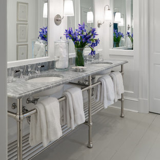 Photo of a mid-sized traditional kids bathroom in Other with recessed-panel cabinets, white cabinets, an alcove tub, an alcove shower, a two-piece toilet, white walls, painted wood floors, an undermount sink, marble benchtops, grey floor, a sliding shower screen, white benchtops, a double vanity, a freestanding vanity and panelled walls.