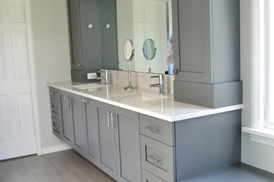 Diseño de cuarto de baño tradicional renovado con lavabo bajoencimera, armarios estilo shaker, puertas de armario grises, encimera de cuarzo compacto, paredes grises y suelo de baldosas de porcelana