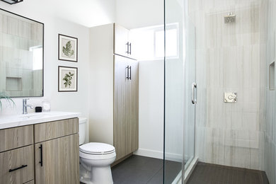 Medium sized coastal ensuite bathroom in Los Angeles with flat-panel cabinets, grey cabinets, a corner shower, white tiles, porcelain tiles, white walls, porcelain flooring, a submerged sink, engineered stone worktops, grey floors, a hinged door and white worktops.