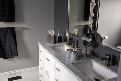他の地域にあるコンテンポラリースタイルのおしゃれな浴室 (白いキャビネット、グレーの壁、アンダーカウンター洗面器、珪岩の洗面台、白い床、グレーの洗面カウンター) の写真