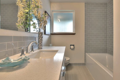Ejemplo de cuarto de baño minimalista de tamaño medio con puertas de armario blancas, sanitario de una pieza, baldosas y/o azulejos grises, baldosas y/o azulejos de cemento, paredes beige y lavabo integrado