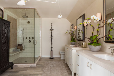 Réalisation d'une salle de bain principale de taille moyenne avec des portes de placard blanches, une baignoire indépendante, une douche d'angle, un mur beige, un lavabo encastré et une cabine de douche à porte battante.