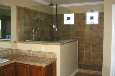 Diseño de cuarto de baño principal clásico grande con armarios con paneles con relieve, puertas de armario de madera oscura, ducha esquinera, paredes beige, encimera de azulejos y ducha abierta